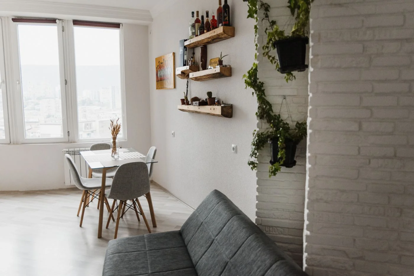 Esstisch und graues Sofa im gemeinsamen Wohnbereich einer hellen Wohnung