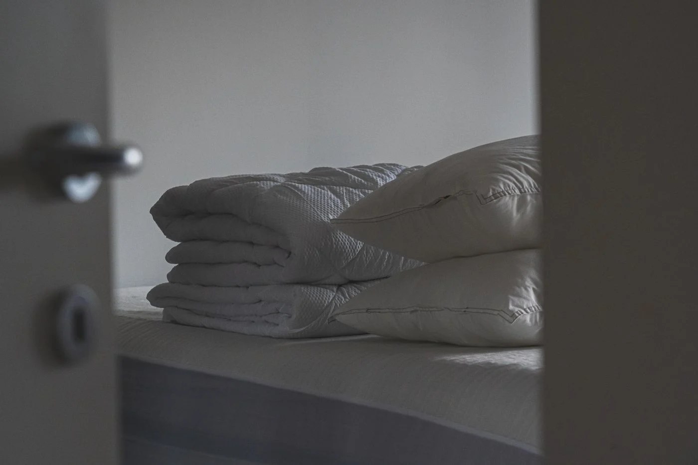 Kissen und gefaltete Bettwäsche auf einem Bett