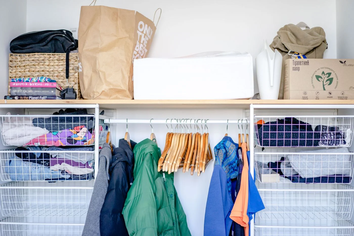 Offener Kleiderschrank mit Kleidung und Körben