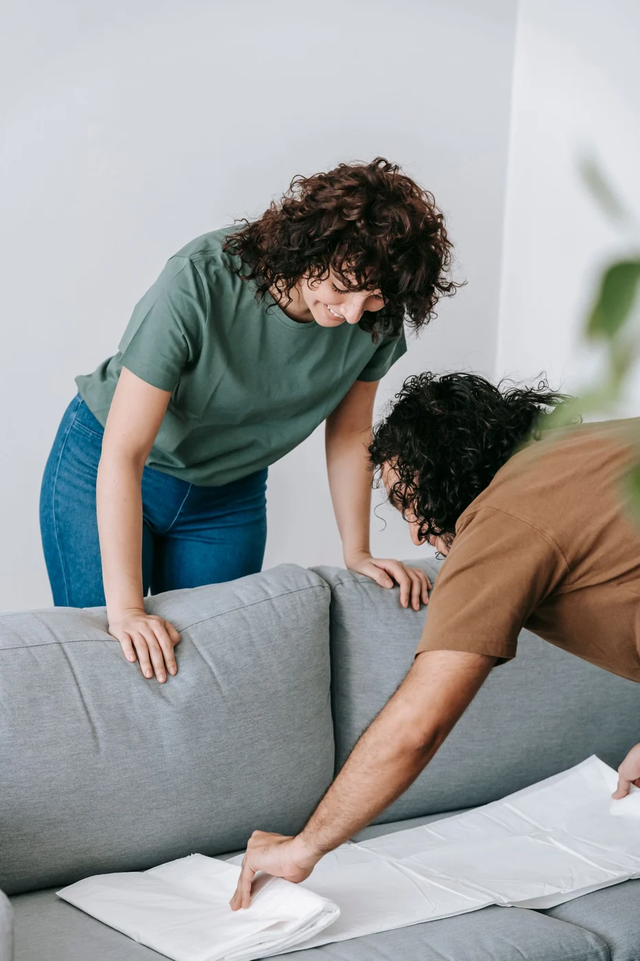 Zwei Personen schützen ein Sofa mit einer Stoffabdeckung